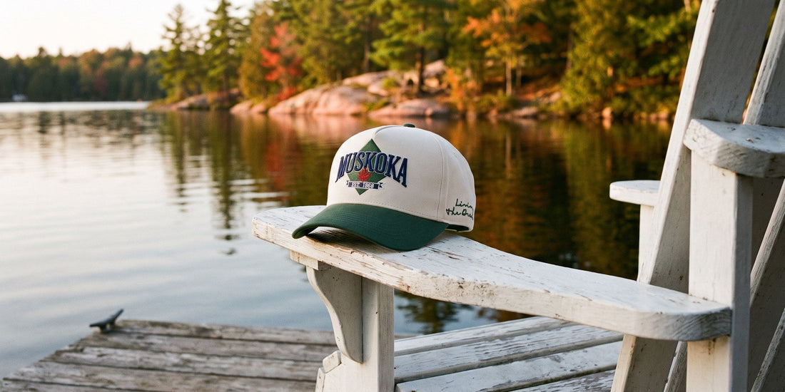 The TEAMLTD Muskoka Snapback resting on the arm of a Muskoka chair on a cottage dock, fall colours on the lake behind